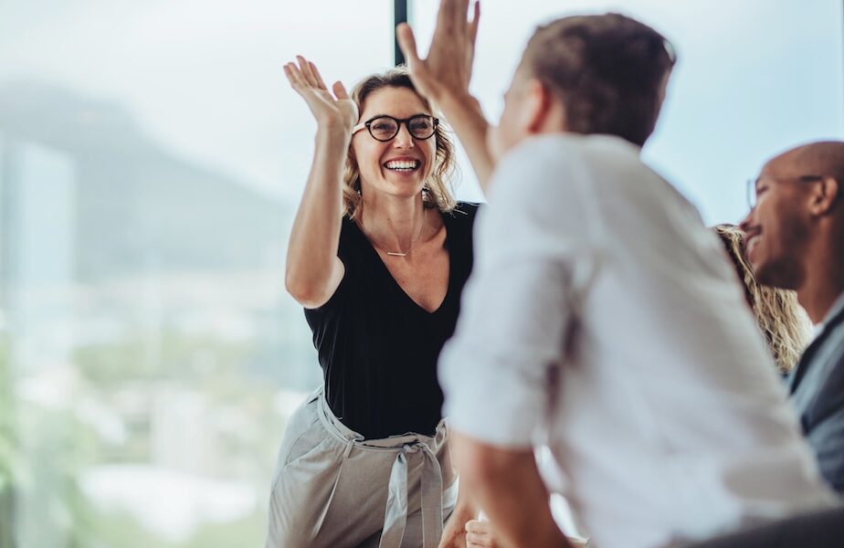 Businesswoman giving a high five to male colleague in meeting. Business professionals high five during a meeting in boardroom.