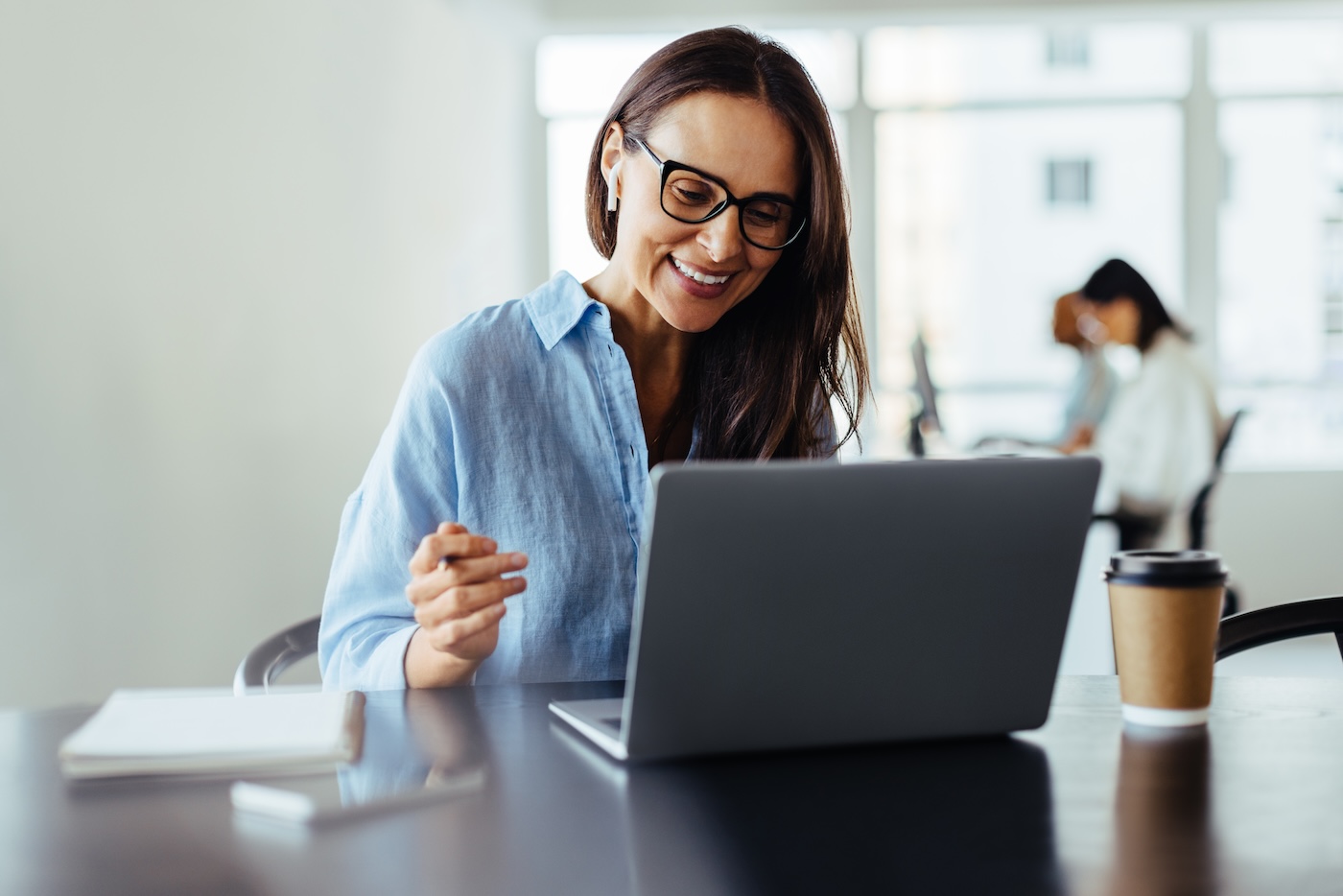 Woman having an online business meeting while sitting in an office. Business woman discussing a new project with her clients on a video call.
